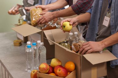 Gönüllülerden oluşan bir grup yemek bağışını kapalı bir masada paketliyor.
