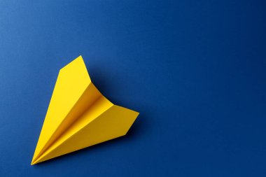 Mavi arka planda el yapımı sarı kağıt uçak, üst manzara. Metin için boşluk