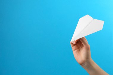 Açık mavi arka planda beyaz kağıt uçaklı kadın, yakın plan. Metin için boşluk