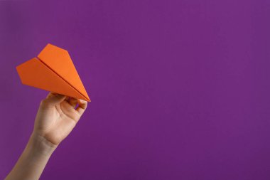 Mor arka planda turuncu kağıt uçaklı kadın, yakın plan. Metin için boşluk