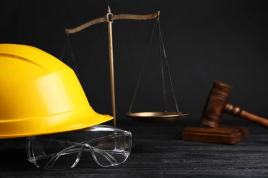 İş yerinde kaza oldu. Gavel, pullar ve inşaat işçilerinin koruyucu giysileri siyah ahşap masada, seçici odaklı.