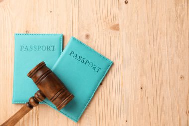 Açık mavi örtülü pasaportlar ve ahşap masadaki yargıç tokmağı, üst manzara. Metin için boşluk