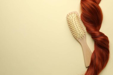 Tahta fırça ve bej arka planda bir tutam saç, üst manzara. Metin için boşluk