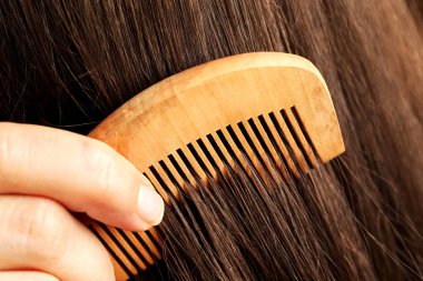Saçlarını ahşap tarakla tarayan kadın, yakın plan.