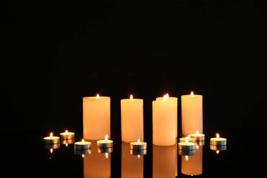 Birçok yanan mum ayna yüzeyinde siyah arkaplana karşı