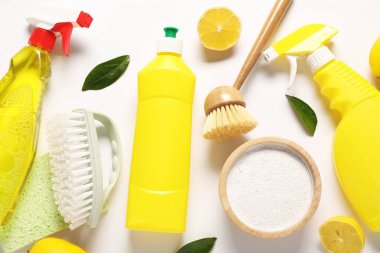 Beyaz zemin üzerinde temizlik ürünleri, araçlar ve limonlar ile düz bileşim yatıyordu