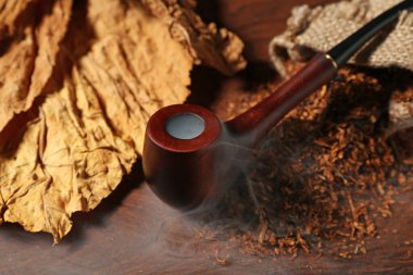 Tütün, kurumuş yapraklar ve sigara piposu ahşap masada, yakın plan.