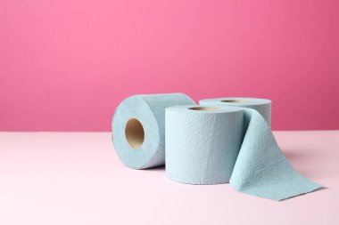 Pembe arka planda mavi tuvalet kağıdı ruloları. Metin için boşluk