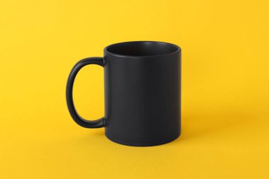 Sarı arka planda boş bir siyah kupa. Tasarım için model