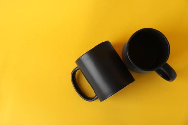 Sarı arka planda iki boş siyah kupa, üst manzara. Tasarım için model
