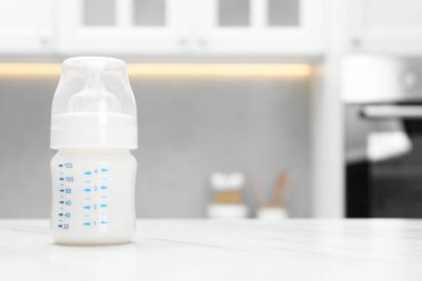 Feeding bottle with milk on white table indoors. Space for text