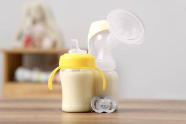 Süt şişeleri, göğüs pompası ve emzik kapalı masa üzerinde emzik