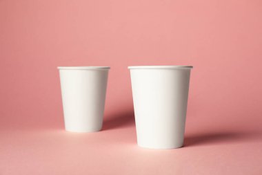 Pembe arka planda kağıt bardaklar. Tasarım için model