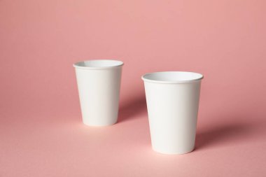 Pembe arka planda kağıt bardaklar. Tasarım için model