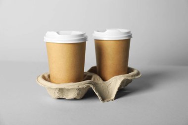 Gri arka planda kapaklı kağıt bardaklar, yakın plan. Tasarım için model