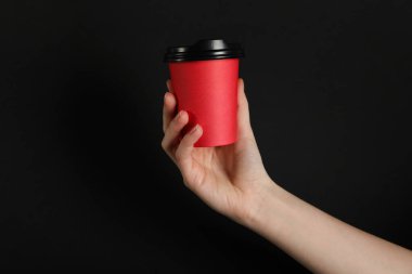 Siyah arka planda kağıt bardak tutan kadın, yakın plan. Tasarım için model