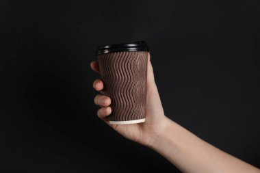 Siyah arka planda kağıt bardak tutan kadın, yakın plan. Tasarım için model