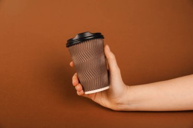 Kahverengi arka planda kağıt bardak tutan kadın, yakın plan. Tasarım için model