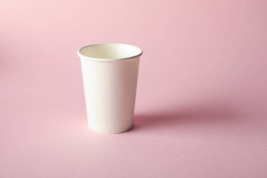 Pembe arka planda bir kağıt bardak. Tasarım için model