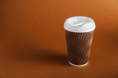 Kahverengi arka planda bir kağıt bardak. Tasarım için model