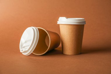 Kahverengi arka planda kapaklı kağıt bardaklar. Tasarım için model