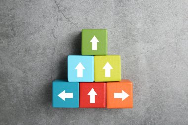 Gri arkaplanda beyaz okları olan renkli küpler, üst görünüm