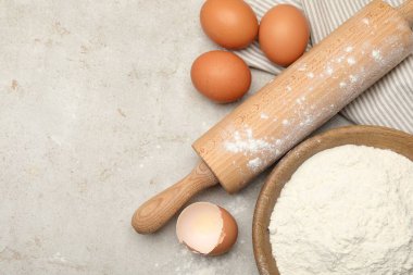 Yuvarlanan iğne, un ve yumurta açık gri arka planda, düz yerde. Metin için boşluk