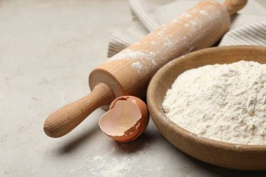 Açık gri arka planda yuvarlanan iğne, un ve yumurta kabuğu, yakın plan. Metin için boşluk