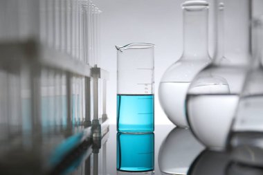 Ayna yüzeyinde ışık arkaplanına karşı sıvı bulunan laboratuvar camları