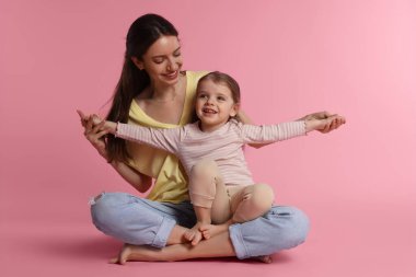 Pembe arka planda küçük tatlı kızı olan mutlu bir anne.