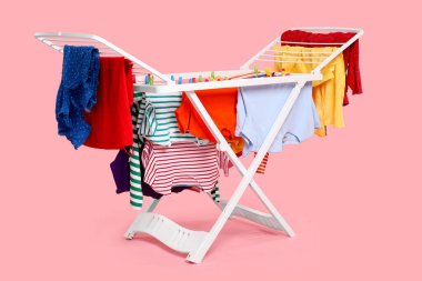 Açık pembe arka planda temiz çamaşırlı kuru askı.