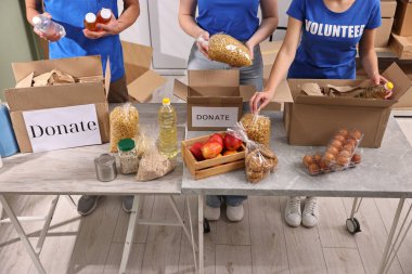 Gönüllüler yemek bağışlarını kapalı masalarda paketliyor.