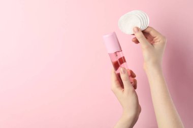 Mikiler suyu ve açık pembe arka planda temiz pamuk pedleri olan bir kadın, yakın plan. Metin için boşluk