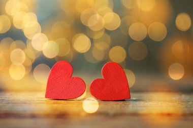Sevgililer Günü tebrik kartı. Masada küçük kırmızı kalpler, bokeh etkisi. Metin için boşluk