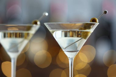 Arka planda bulanık zeytinli martini kokteyli, yakın plan. Bokeh etkisi