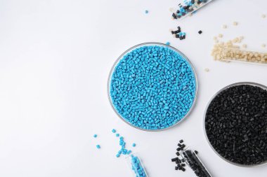 Petri kabında renkli plastik granüller ve beyaz arka planda test tüpleri, düz yatak. Metin için boşluk