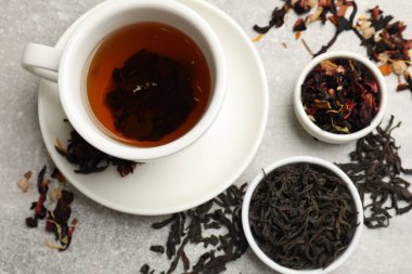 Aromatik çay ve kuru yapraklar gri masada, düz yerde.