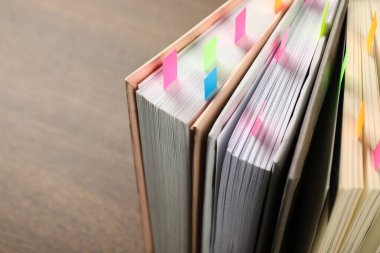 Kahverengi masadaki renkli sekmeli kitaplar, yakın plan. Metin için boşluk