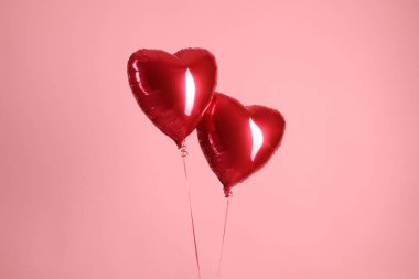 Pembe arka planda iki kırmızı kalp şeklinde balon. Sevgililer Günün kutlu olsun.