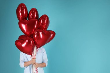 Sevgililer Günün kutlu olsun. Açık mavi arka planda kırmızı kalp şeklinde balonları olan adam, yakın plan. Metin için boşluk
