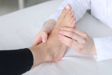 Hastanedeki hastanın ayağını muayene eden doktor, yakın plan.