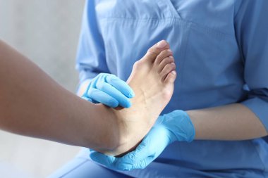 Hastanedeki hastanın ayağını muayene eden doktor, yakın plan.