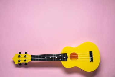 Pembe arka planda bir ukulele, üst manzara. Metin için boşluk