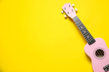 Sarı arka planda bir ukulele, üst manzara. Metin için boşluk