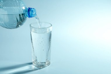 Açık mavi arkaplanda şişeden cama soda dökmek, metin için boşluk