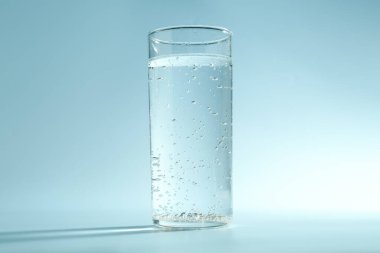 Açık mavi arkaplanda bardakta soda.