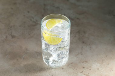 Soda suyunu buz küpleriyle tazelemek ve limonu gri desenli masaya kesip yakın plan yapmak.