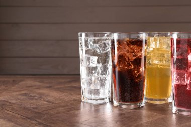 Farklı aromalı soda, ahşap masada buz küpleri, metin için yer.