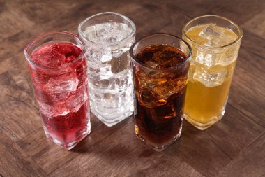 Farklı aromalı soda ve ahşap masada buz küpleri.