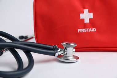 Işık arkaplanı üzerine stetoskop ve ilk yardım kiti, yakın plan